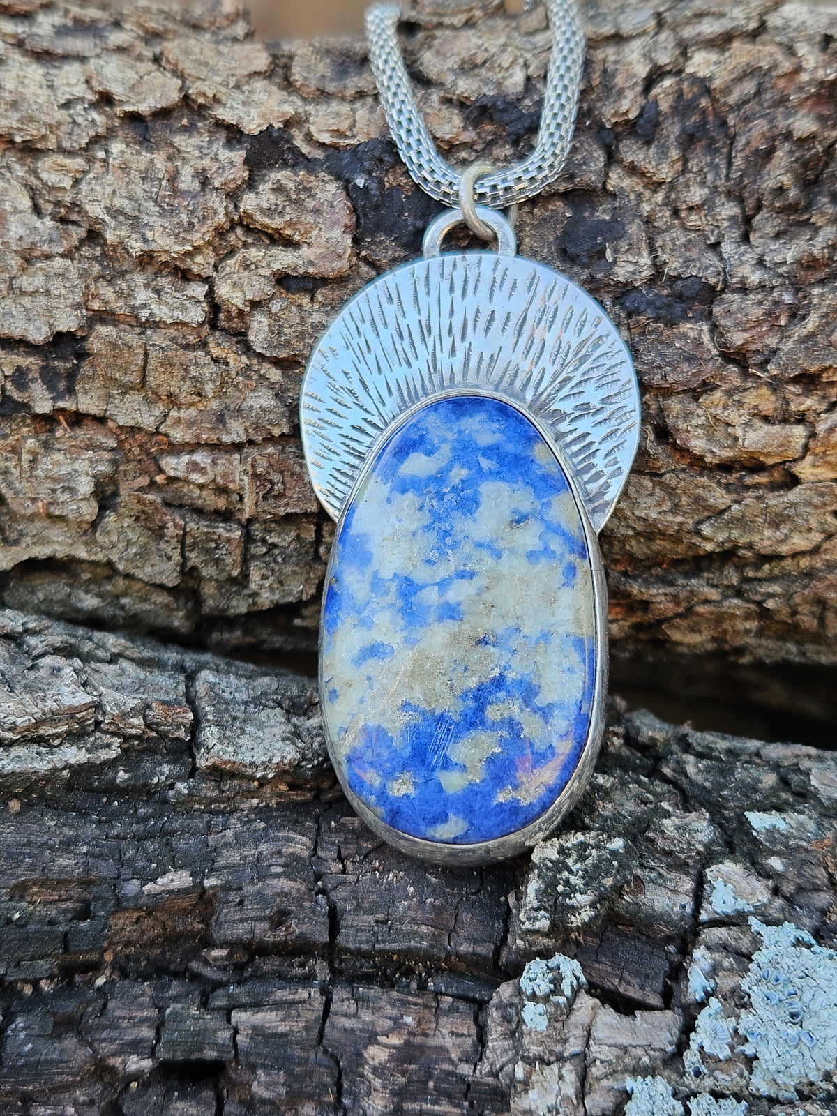 Oval shaped Chilean Lapis Lazuli Pendant set in sterling silver with a silver textured backplate. Blue and White.