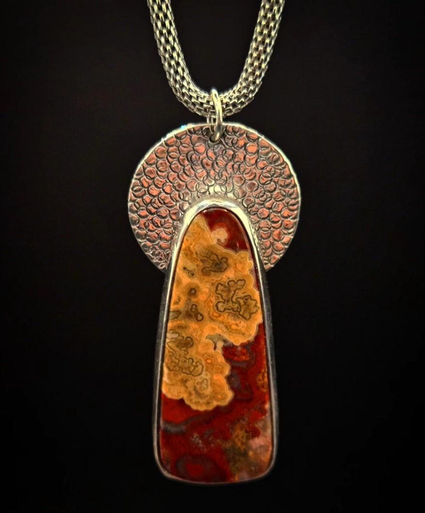 Crazy Lace Agate Pendant set in sterling silver with a textured circular backplate.