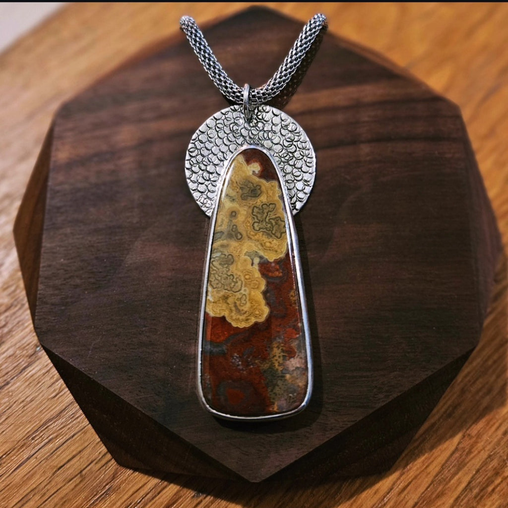 Crazy Lace Agate Pendant set in sterling silver with a textured circular backplate.