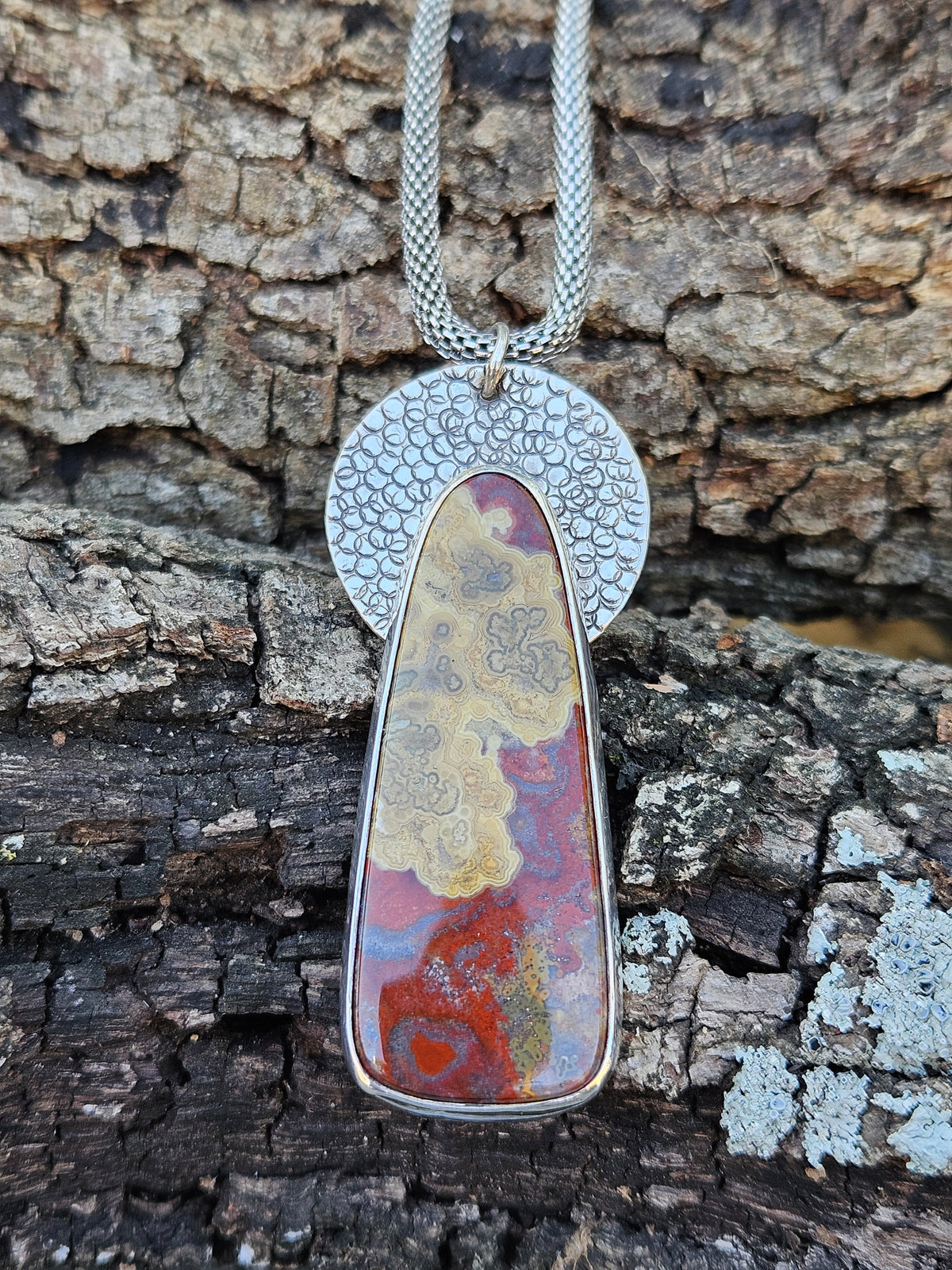 Crazy Lace Agate Pendant set in sterling silver with a textured circular backplate