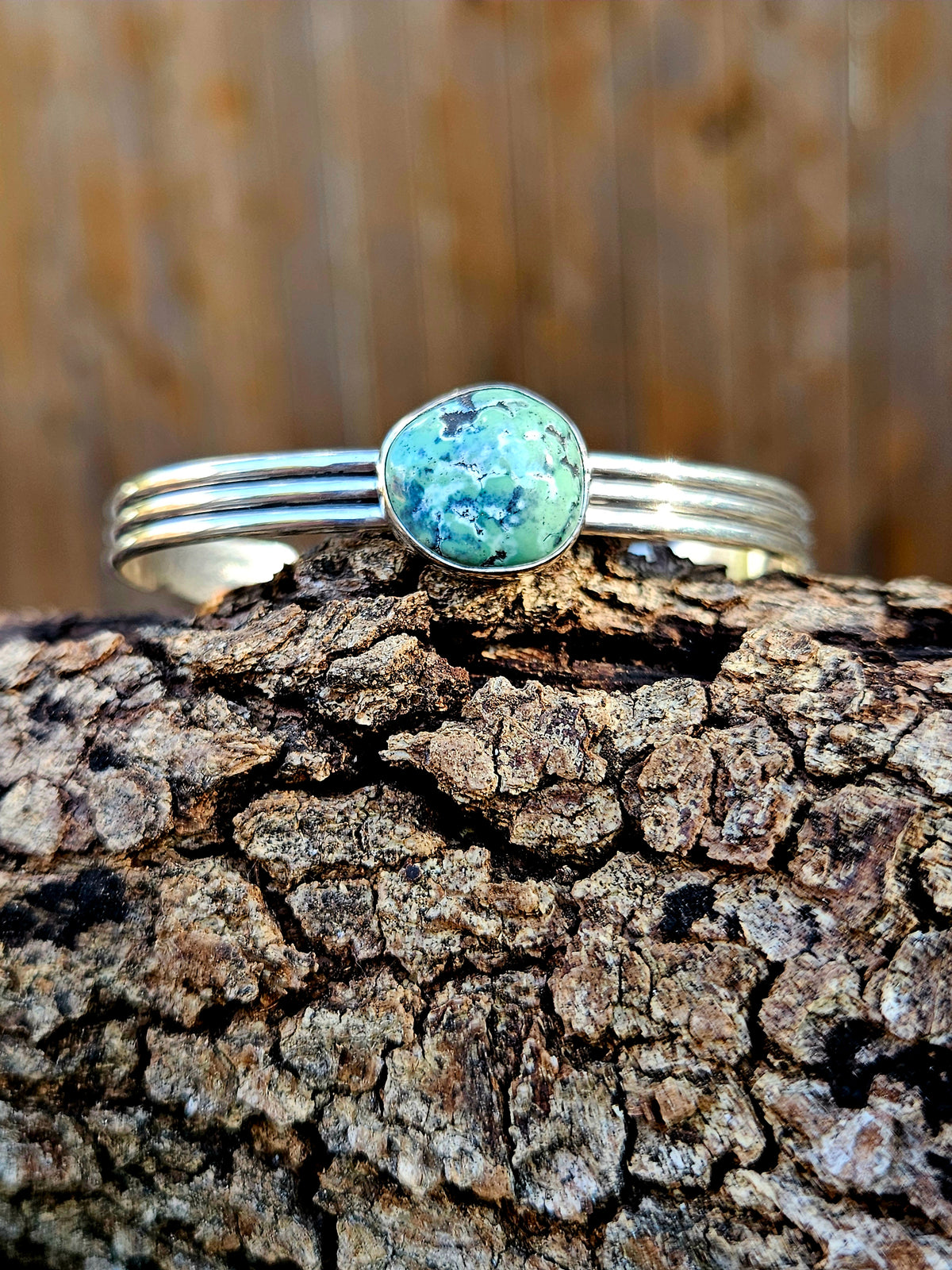 A sterling silver cuff bracelet with a round damele turquoise stone.