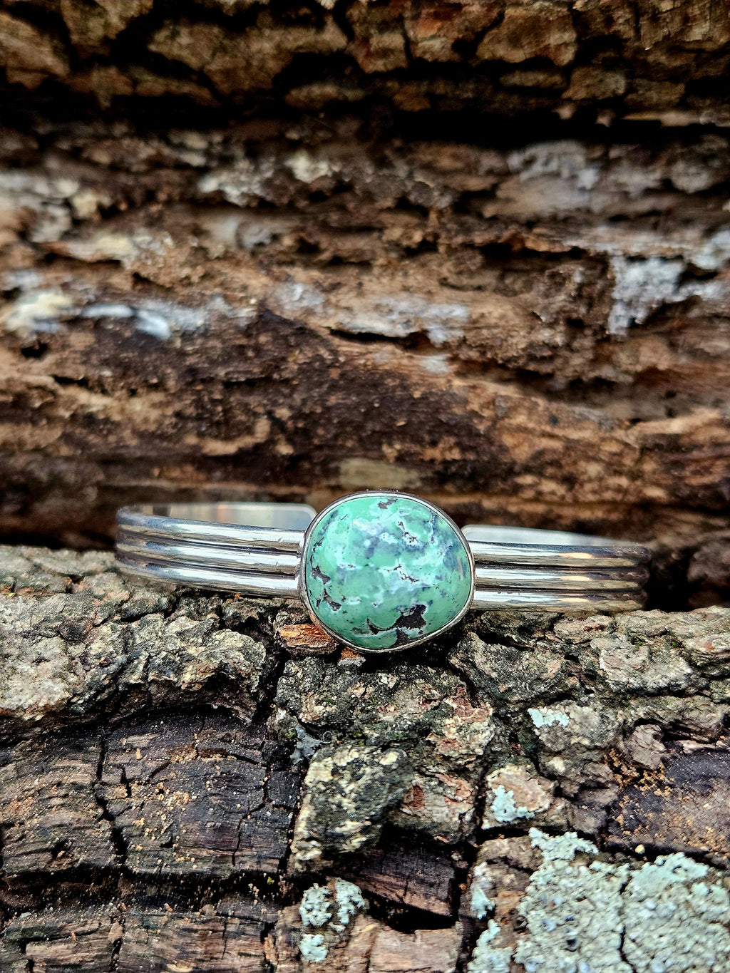 A sterling silver multi-band cuff with a round damale turquoise.