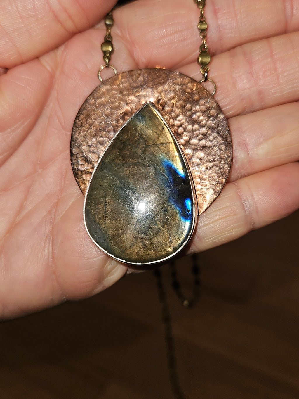 Teardrop-shaped labradorite pendant necklace over a hammered copper disc pendant.