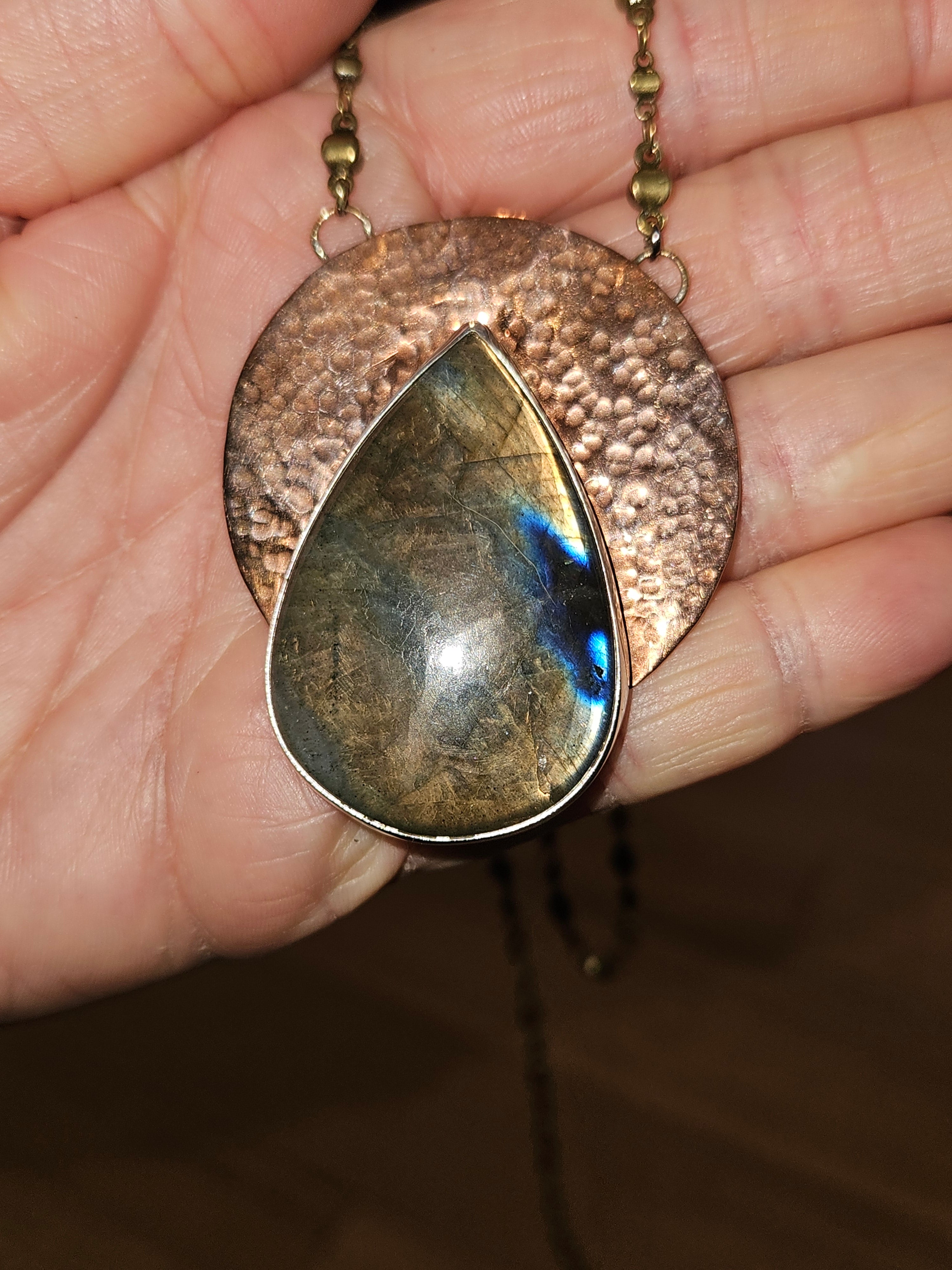 Teardrop-shaped labradorite pendant necklace over a hammered copper disc pendant.