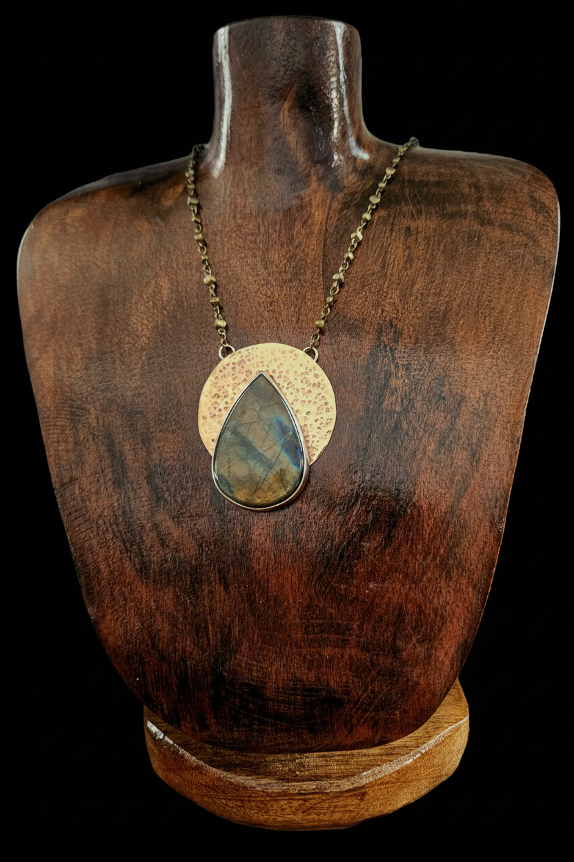 A teardrop-shaped labradorite stone pendant necklace with a textured copper disc and brass chain.