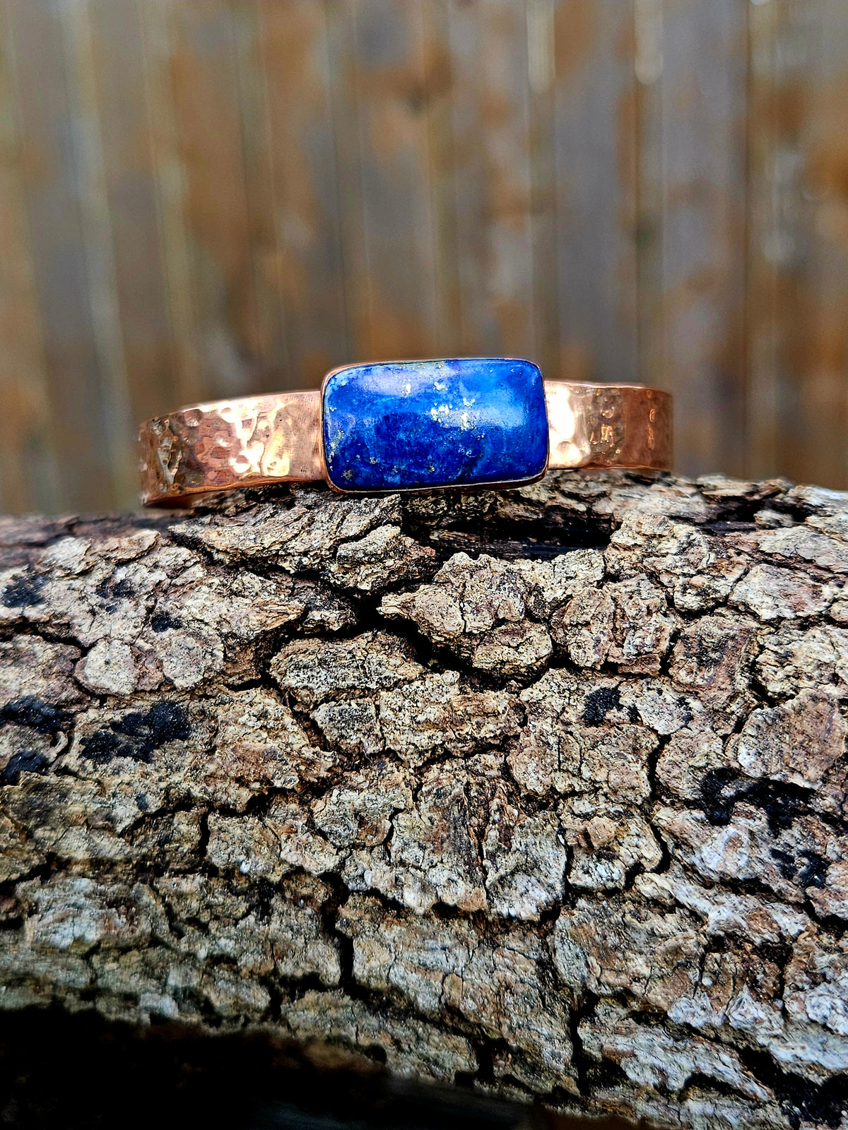 A hammered copper cuff with a rectangular blue lapis Lazuli set in the middle.