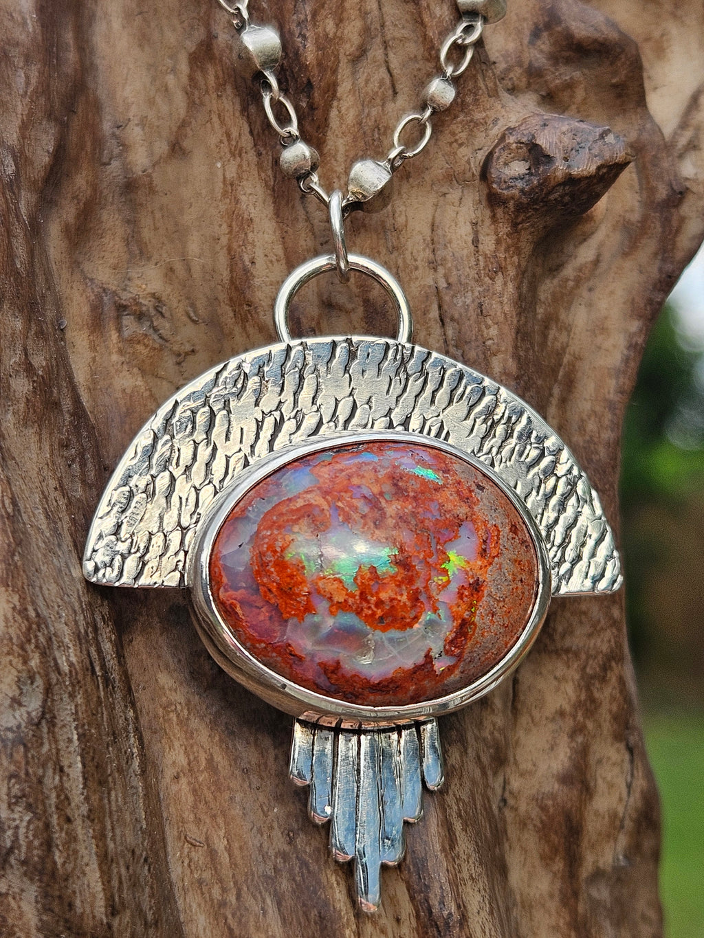Sterling silver mexican matrix opal pendant with a textured backplate.