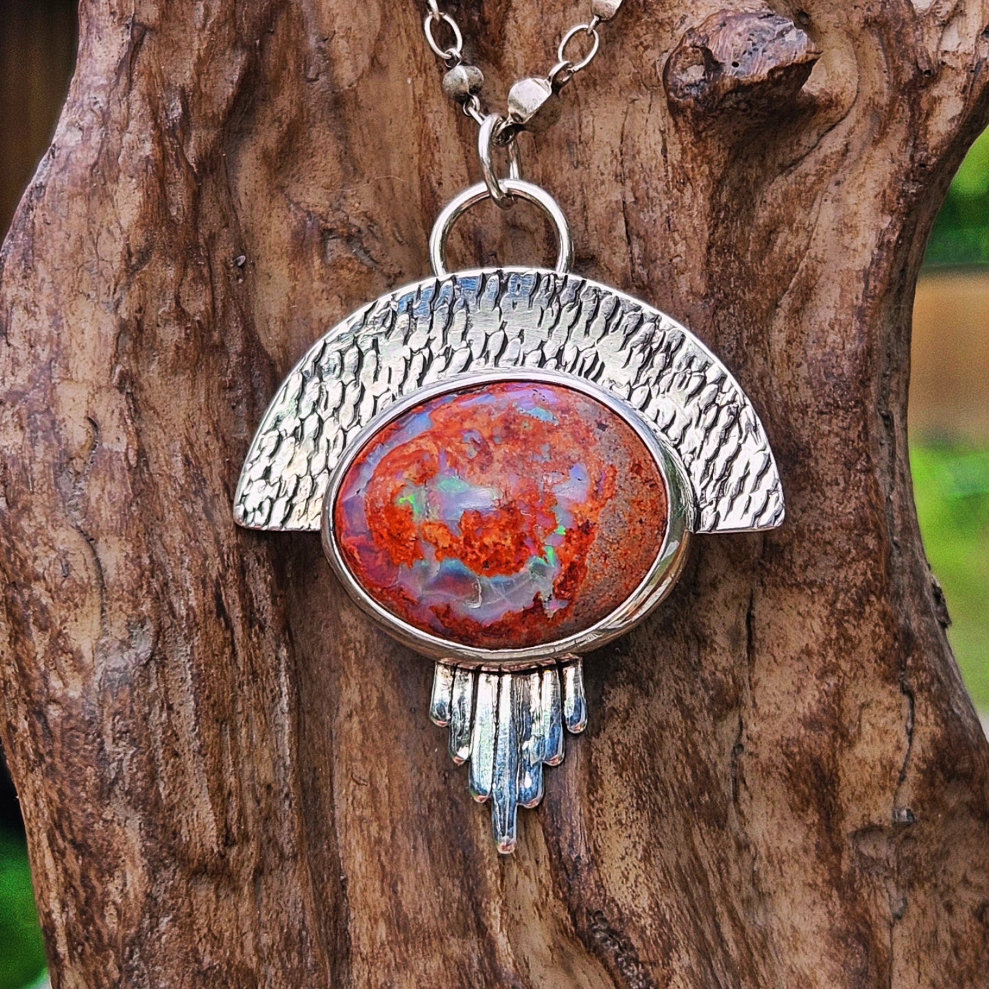 Sterling silver mexican matrix opal pendant with a textured backplate.