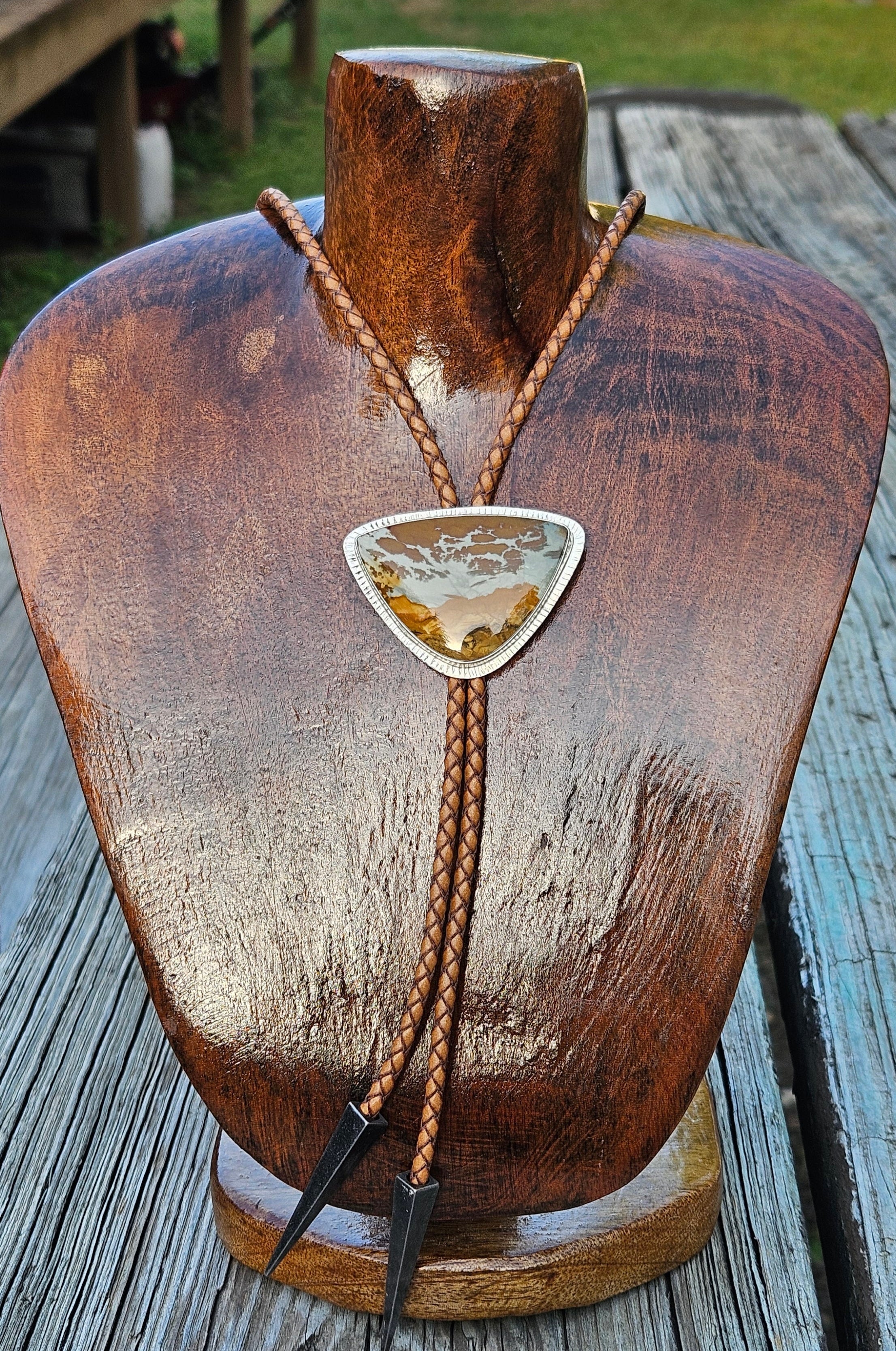 Owyhee Blue Sky Picture Jasper Bolo set in sterling silver with a textured border and a light brown leather cord with triangular antique silver tips.