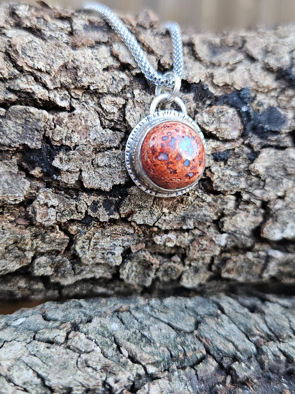 Round Mexican Matrix Opal Pendant set in sterling silver with a textured border. 