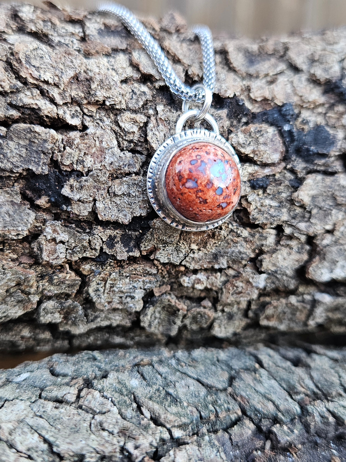 Round Mexican Matrix Opal Pendant set in sterling silver with a textured border. 