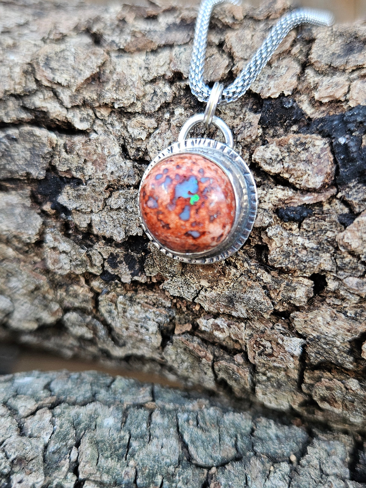 Round Mexican Matrix Opal Pendant set in sterling silver with a textured border. 