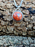 Round Mexican Matrix Opal Pendant set in sterling silver with a textured border. 