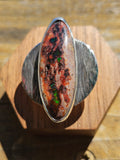 Mexican Matrix Opal Ring in sterling silver with a textured silver backplate. The opals matrix is brown and has pockets of red and green colors. Size 10