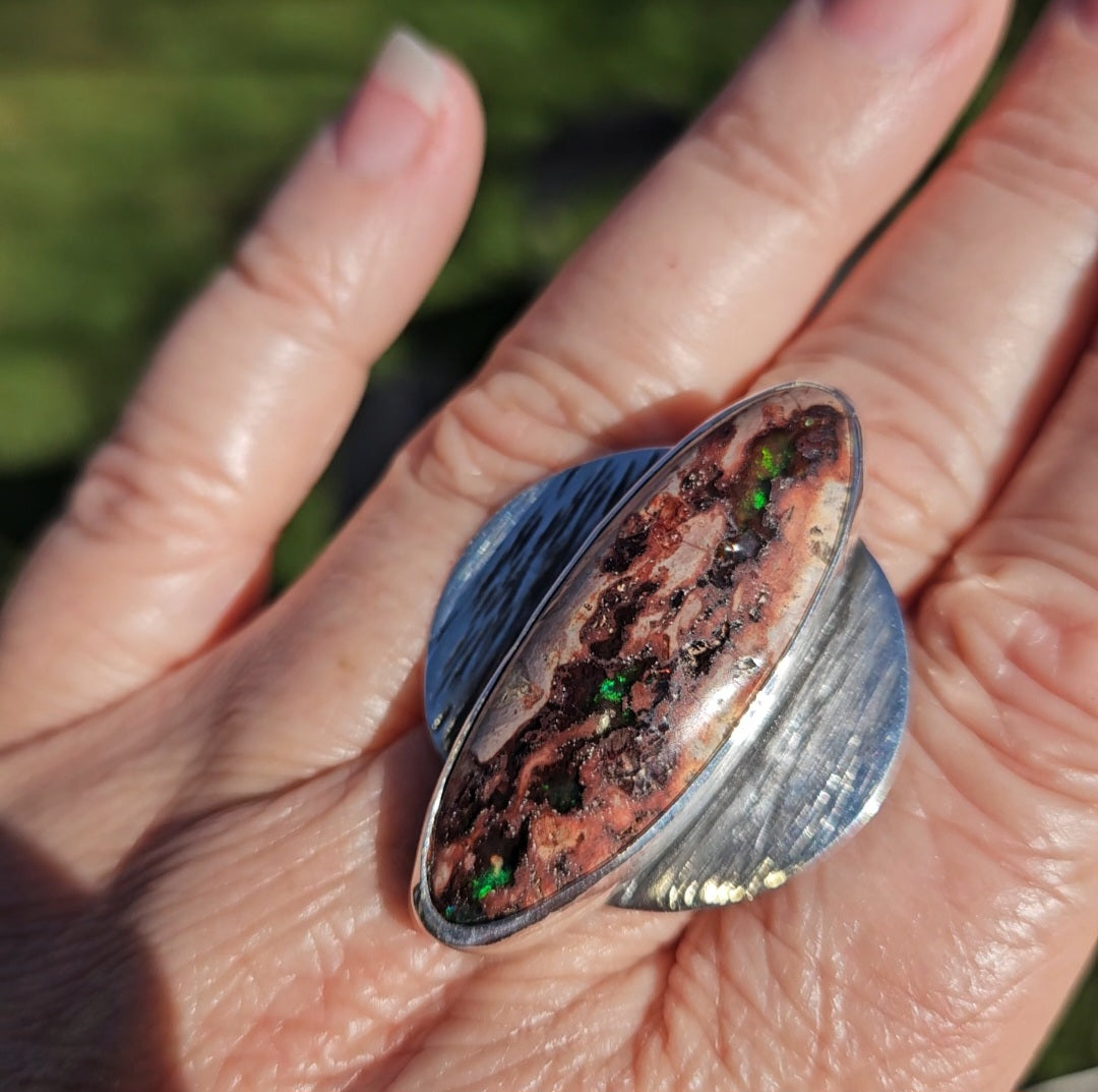 Large sterling silver ring with an oval cabochon featuring a Mexican Matrix Opal textured brown and black pattern with small green inclusions.  Size 10