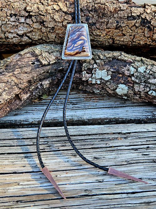 Rectangular sterling silver Biggs Jasper Bolo with black leather cord and copper triangular tips.