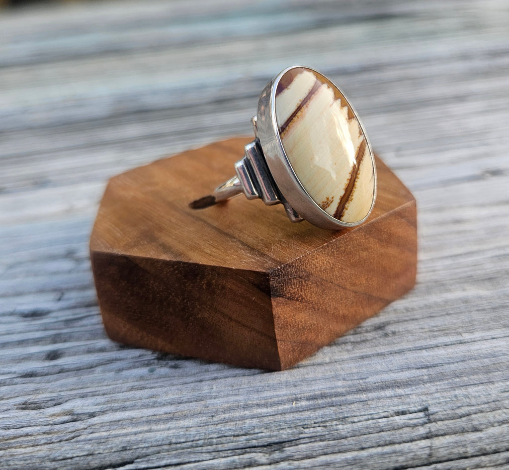 A silver ring with a large oval cabochon featuring a cream and brown striped pattern of picture jasper. 