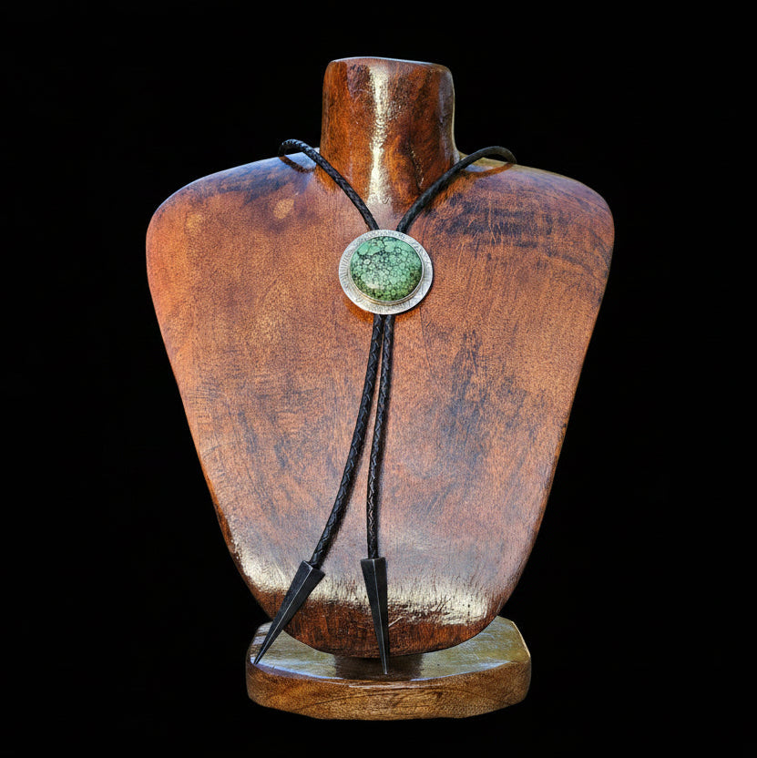 Round Hubei Spideweb Turquoise Bolo set in sterling silver with a textured border and black leather cord with triangular antique silver tips.