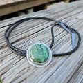 Round Hubei Spiderweb Turquoise Bolo set on sterling silver with a black braided leather cord and triangular antique silver tips 
