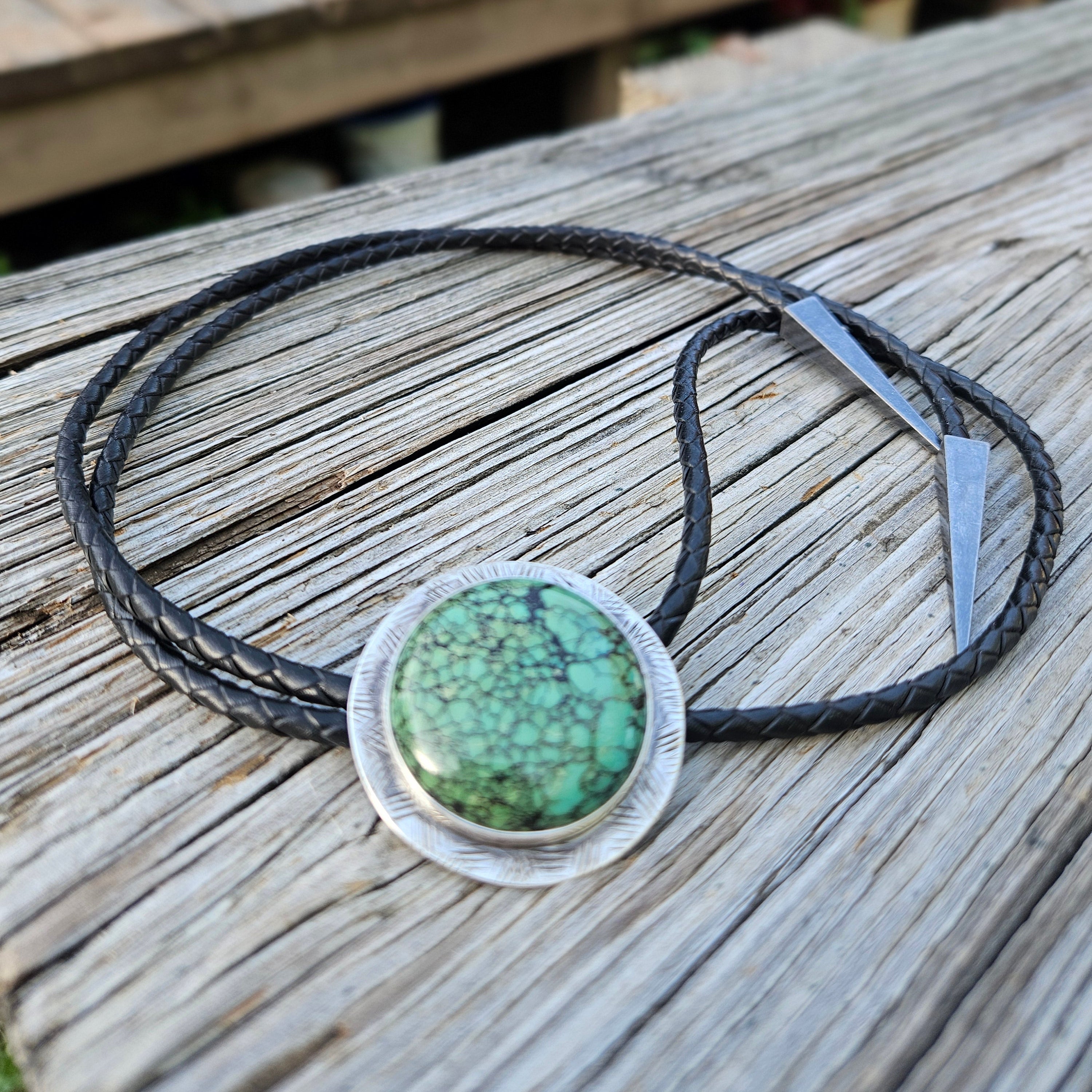 Round Hubei Spiderweb Turquoise Bolo set on sterling silver with a black braided leather cord and triangular antique silver tips 